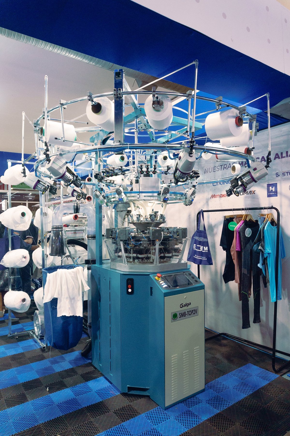 Stand showroom de Grupo Galga con maquinaria textil y prendas